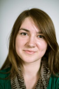 Portrait of a real young woman on a light background in a green cardigan. Shallow depth of field.